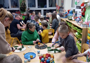 Rodzice z dziećmi wykonują stroiki świąteczne