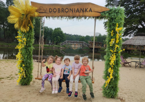 Dzieci siedzą na huśtawce z napisem Dobronianka