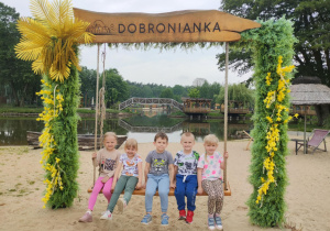 Dzieci siedzą na huśtawce z napisem Dobronianka