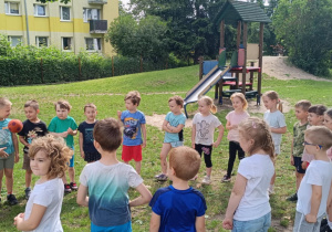 Dzieci podają sobie piłkę w kole