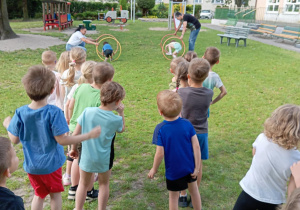 Dzieci ścigają się w rzędach, aby przejść przez obręcze