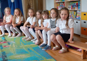 Dziewczynki siedzą na ławce podczas przedstawienia