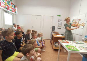 Dzieci słuchają książki czytanej przez panią bibliotekarkę