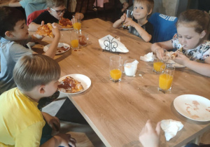 Dzieci jedzą pizzę