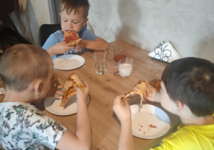 Trzech chlopców je pizzę