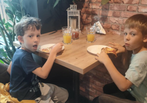 Dwóch chłopców je pizzę