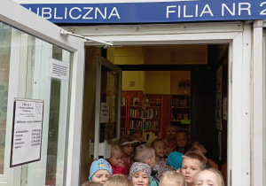Dzieci stoją w wejściu do biblioteki