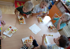 Dzieci jedzą przygotowane przez siebie szaszłyki