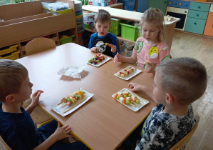 Dzieci jedzą przygotowane przez siebie szaszłyki