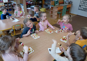 Dzieci jedzą przygotowane przez siebie szaszłyki