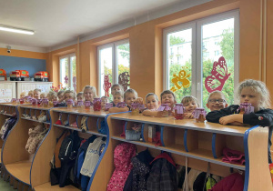 Dzieci pokazują swoje słoiki ustawione w szatni
