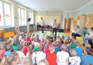 Dzieci siedzą na dywanie podczas koncertu