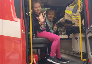 Dziewczynki siedzą w wozie strażackim