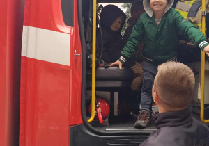 Chłopiec stoi w wozie strażackim