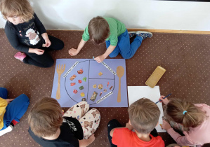 Dzieci z grupy IV naklejają obrazki na rysunkowy talerz