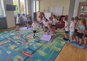 Dzieci w trzech grupach biorą udział w konkurencji przekładania maty