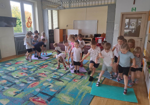 Dzieci w trzech grupach biorą udział w konkurencji przekładania maty
