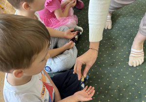 Nauczycielka sypie brokat na rękę dzieci