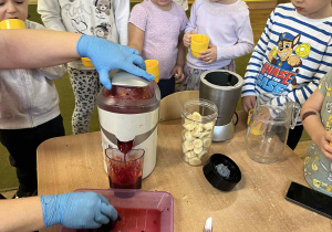 Dzieci z grupy I patrzą jak robi się sok w sokowirówce