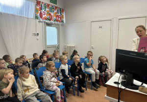Dzieci słuchają książaki czytanej przez panią bibliotekarkę