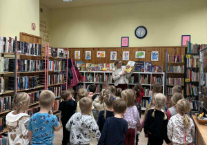 Dzieci oglądają zbiory książek w bibliotece