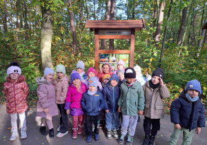 Dzieci stoją przy tablicy edukacyjnej o zwierzętach leśnych