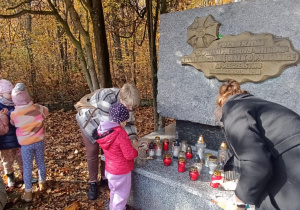 Dzieci zapalają znicze przy pomniku 15 pułku Wilków