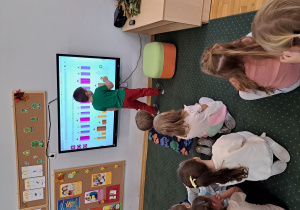 Dzieci rozwiązują zadania z kredkami na tablicy multimedialnej