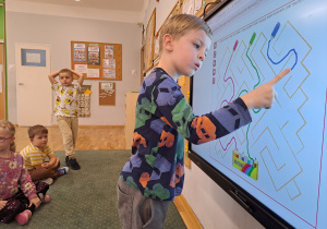 Dzieci rozwiązują zadania z kredkami na tablicy multimedialnej