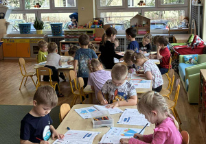 Dzieci wykonują karty pracy z kredkami