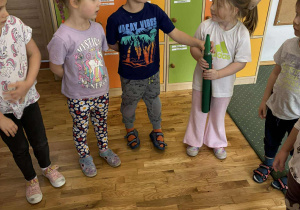 Dzieci podają sobie dużą kredkę w kole