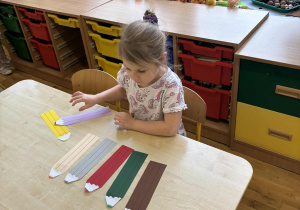 Dziewczynka dobiera kolorowe kredki według wzoru