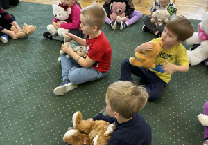 Dzieci siedzą na dywanie z misiami