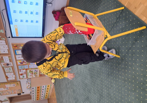 Chłopiec próbuje złapać rękawicą kuchenną kredkę