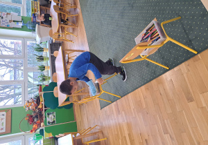 Chłopiec próbuje złapać rękawicą kuchenną kredkę