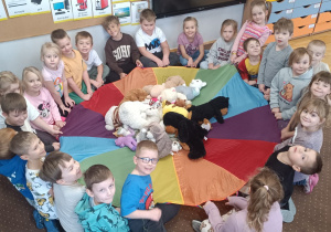 Dzieci podrzucają misie na chuście