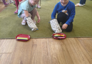 Dzieci próbują złapać kredki rękawicą kuchenną