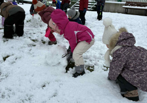 Dzieci toczą kule ze śniegu