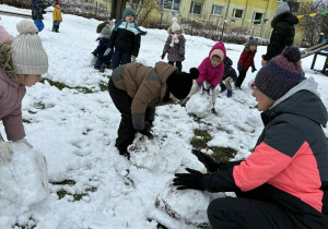 Dzieci toczą kule śnieżna