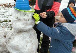 Chłopiec wbija patyk w bałwana