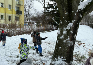 Dzieci rzucają śnieżki w drzewo