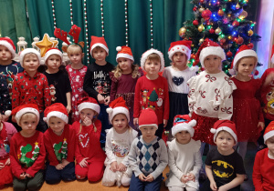 Dzieci z grupy II stoją przed ścianką świąteczną