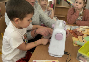 Chłopiec uczy się szyć na maszynie