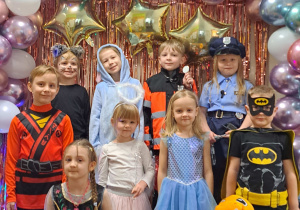 Dzieci z grupy III pozują przy ściance karnawałowej do zdjęć