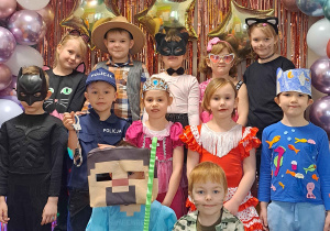 Dzieci z grupy IV pozują przy ściance karnawałowej do zdjęć