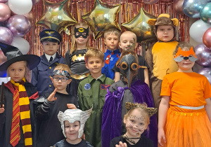 Dzieci z grupy IV pozują przy ściance karnawałowej do zdjęć