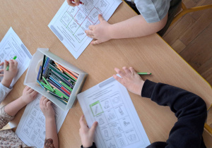 Dzieci kolorują karty pracy