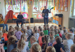 Dzieci siedzą na dywanie podczas koncertu