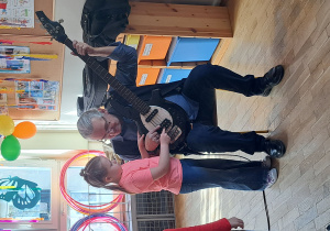 Dziewczynka próbuje grać na gitarze