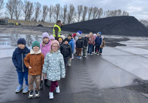 Dzieci stoją na tle hałdy węgla